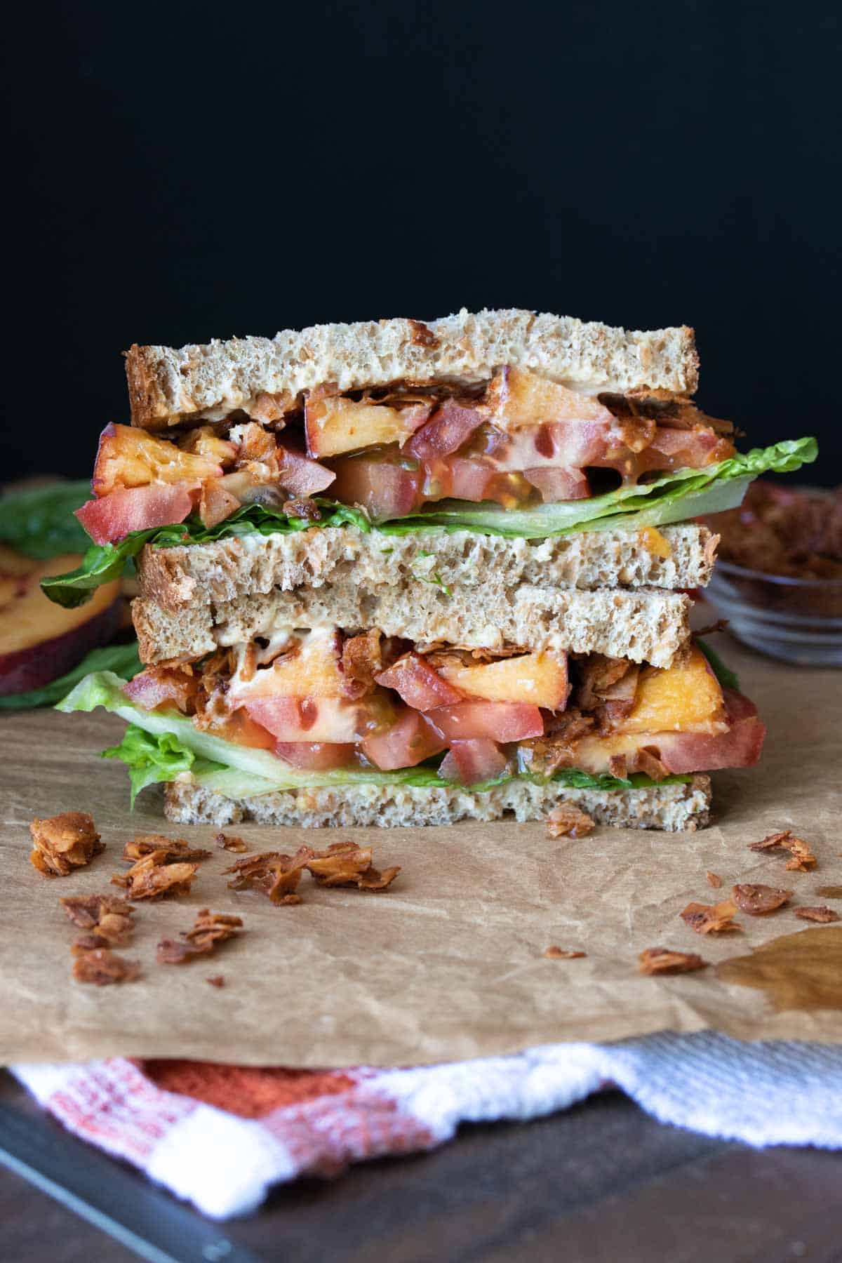 Two halves of a coconut bacon BLT with peaches, stacked on top of each other