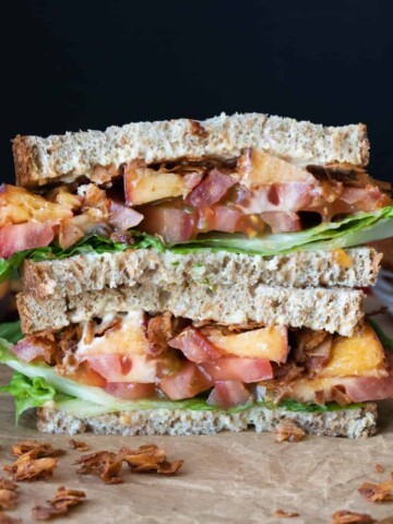 Two halves of a sandwich with coconut bacon and peaches stacked on top of each other