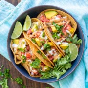 Three fully loaded potato tacos in a dark blue dish