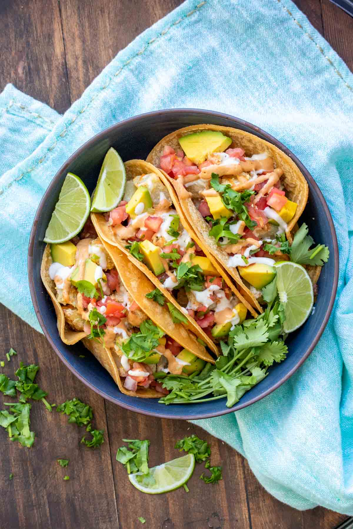 Three fully loaded potato tacos in a dark blue dish