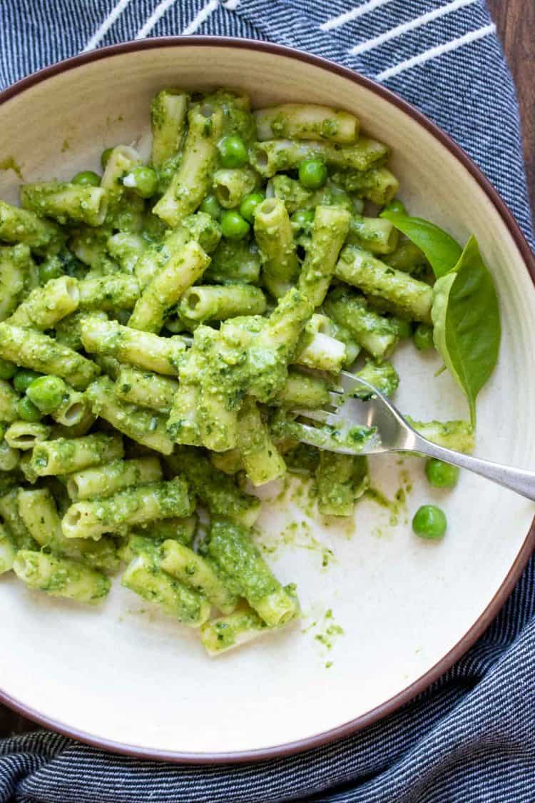 Fork getting a bite of pasta mixed with pesto and peas