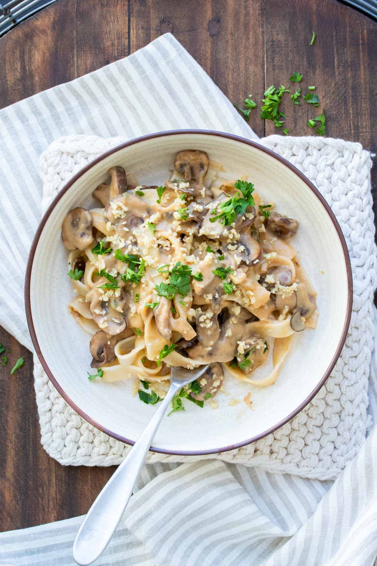 White bowl filled with fettuccini noodles and mushroom stroganoff sauce