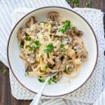 White bowl filled with mushroom stroganoff and topped with chopped parley.