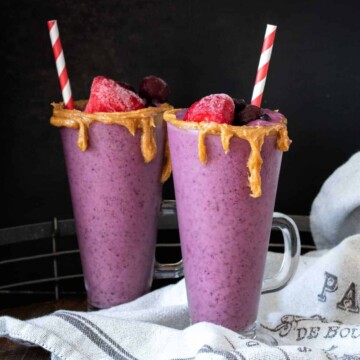 Two PB&J smoothies in glasses with a red striped straw in them