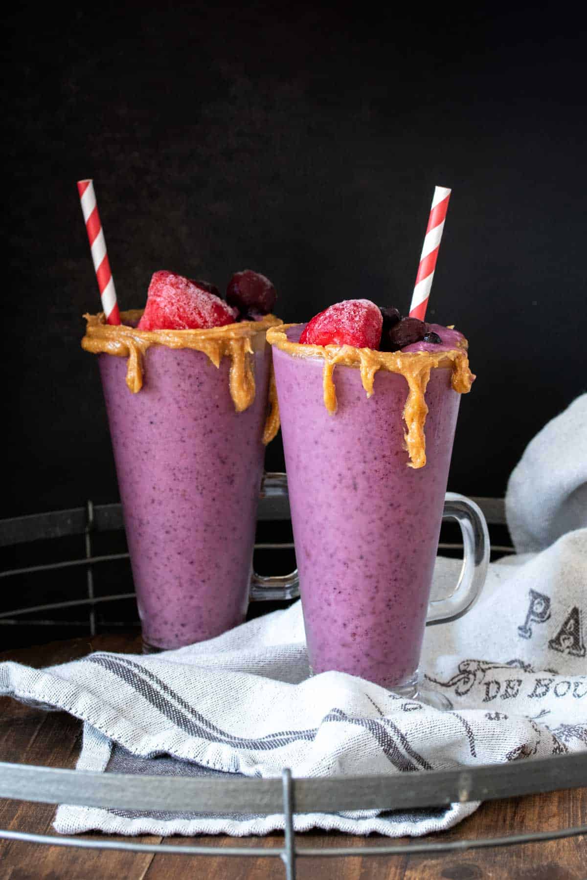 Two PB&J smoothies in glasses with a red striped straw in them