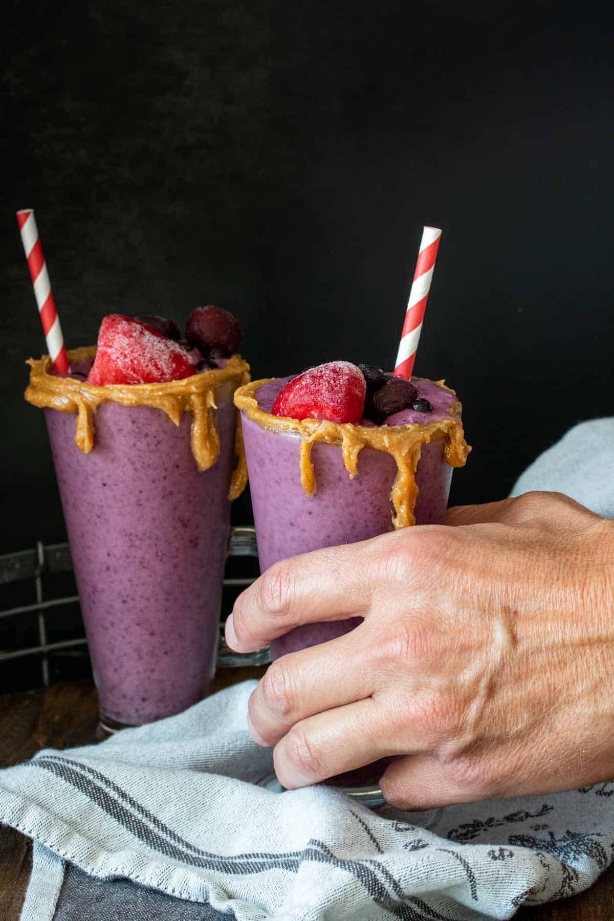 Hand grabbing a glass of PB&J smoothie