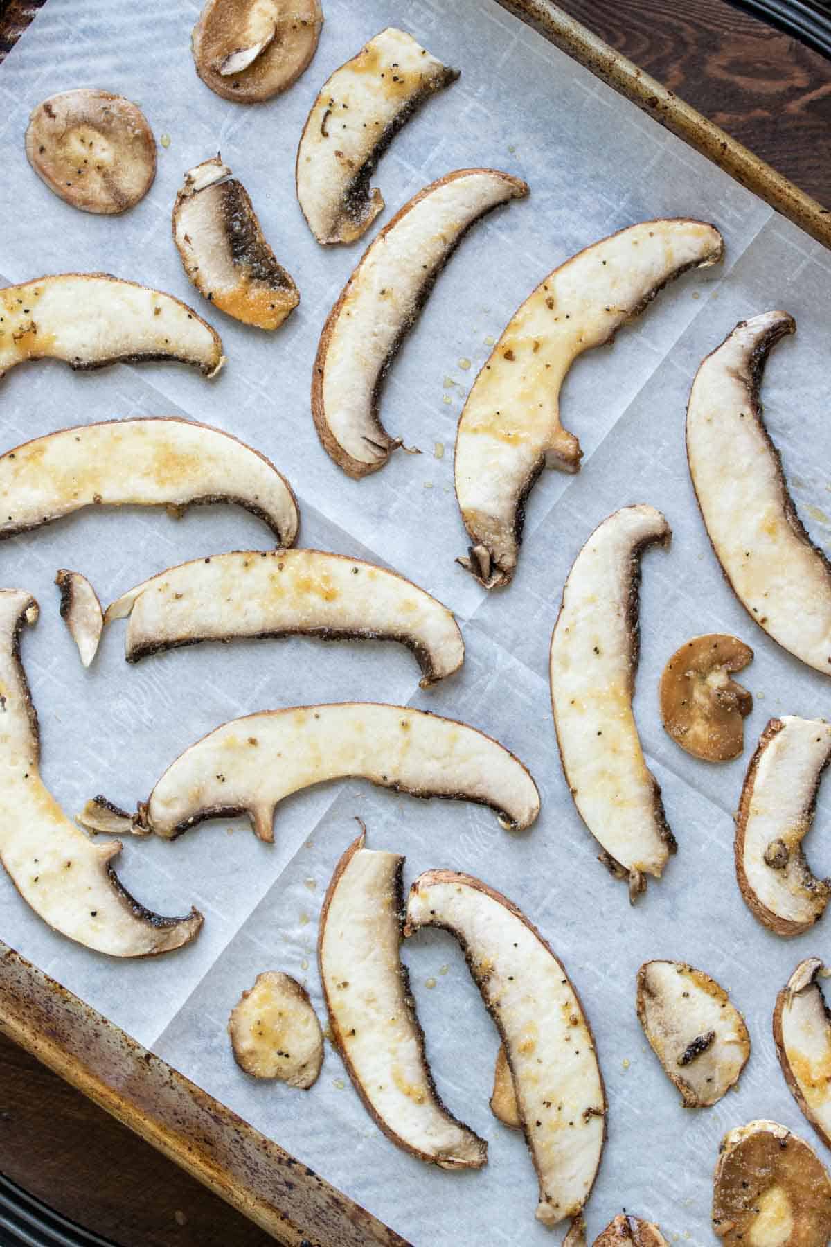 Slices of portobello mushroom on a piece of parchment paper on a baking sheet