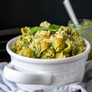 White bowl with handles filled with pesto covered pasta