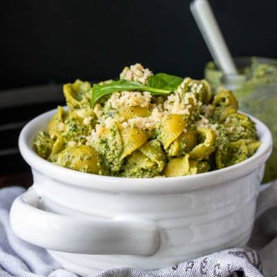 White bowl with handles filled with pesto covered pasta