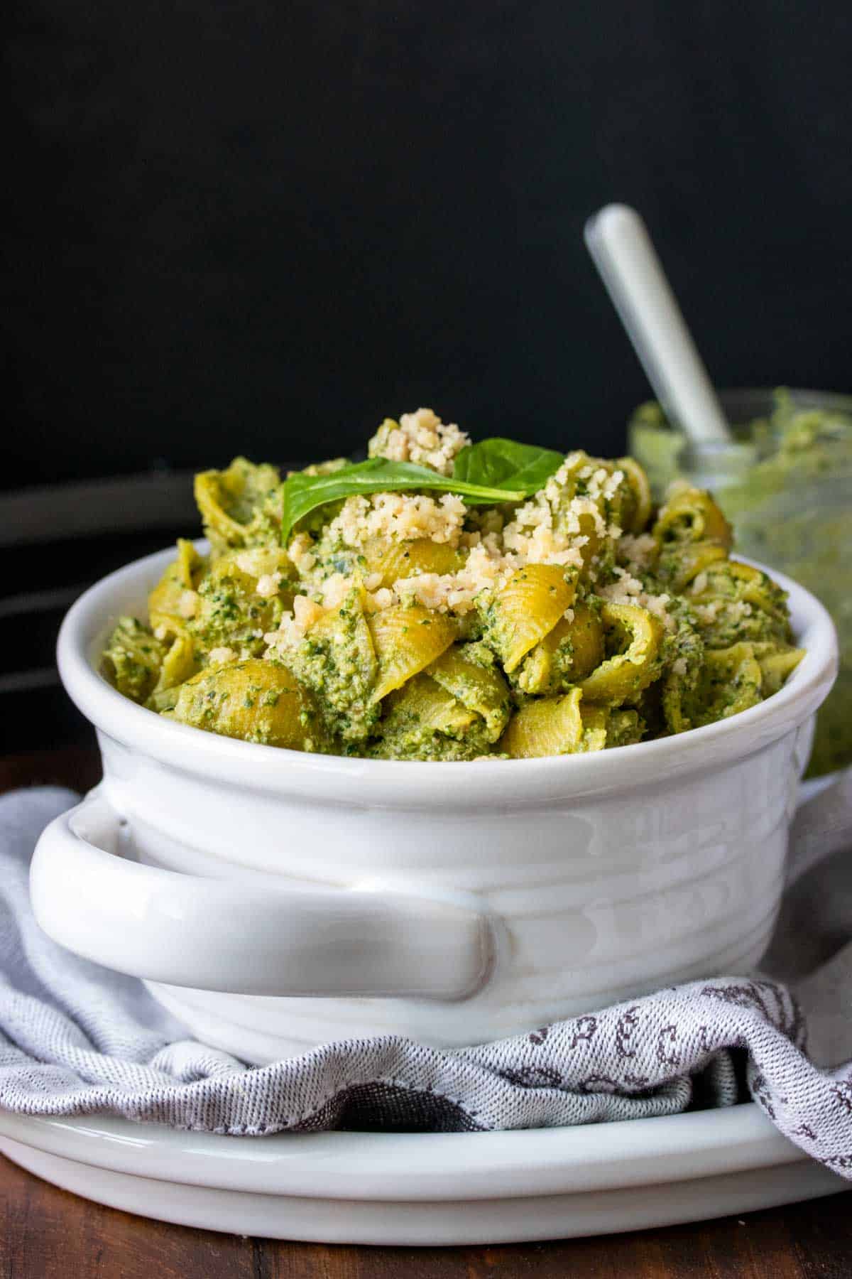 White bowl with handles filled with pesto covered pasta