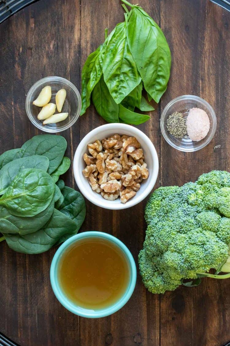 Ingredients to make a broccoli and spinach pesto on a wooden surface