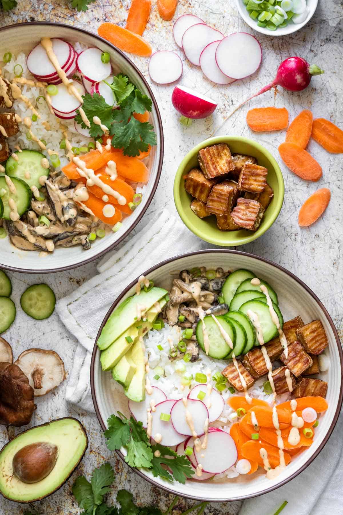 A veggie filled sushi bowl drizzled with sauce and a fork in it