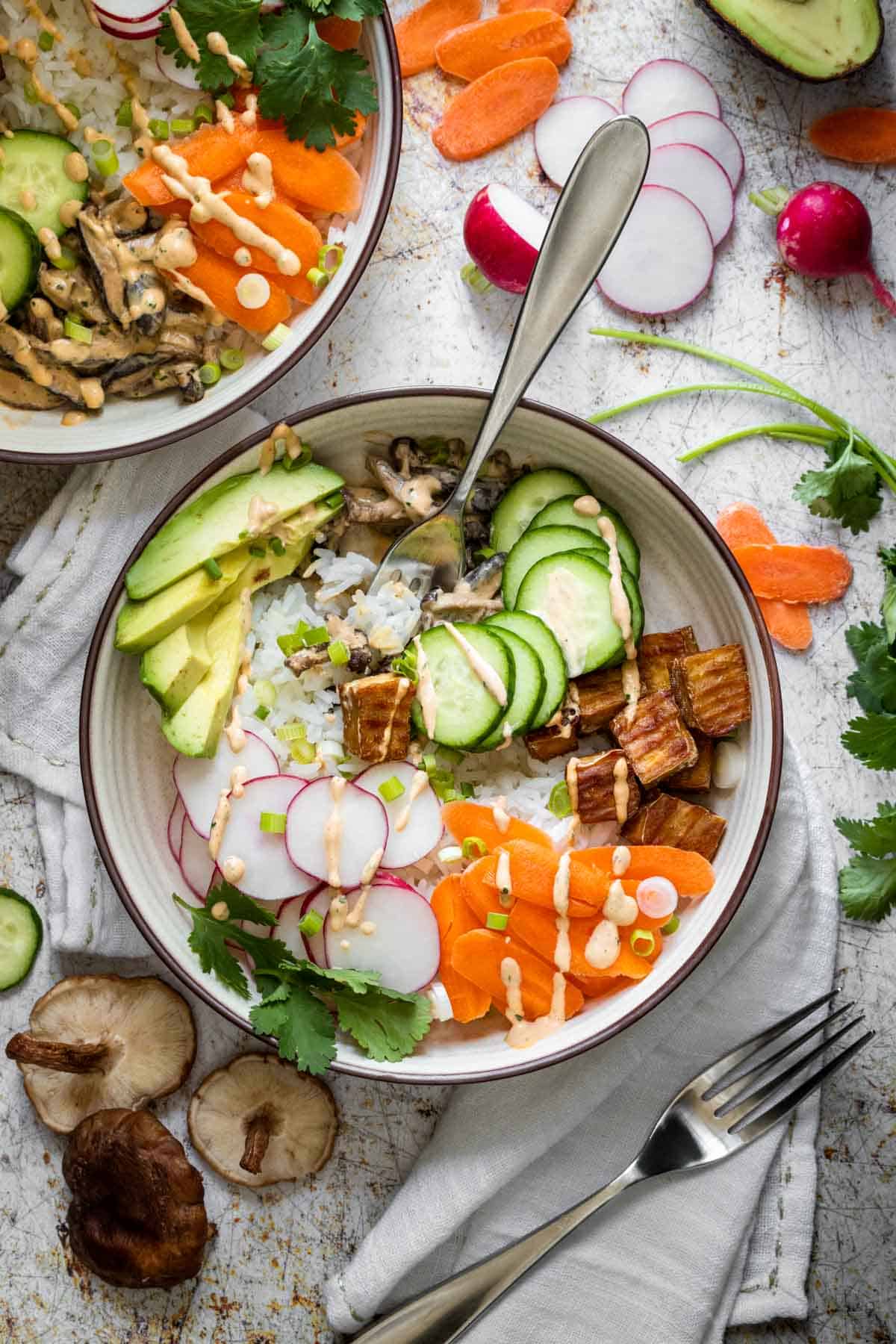 A cream bowl on a white towel with a deconstructed sushi bowl in it and a fork getting a bite