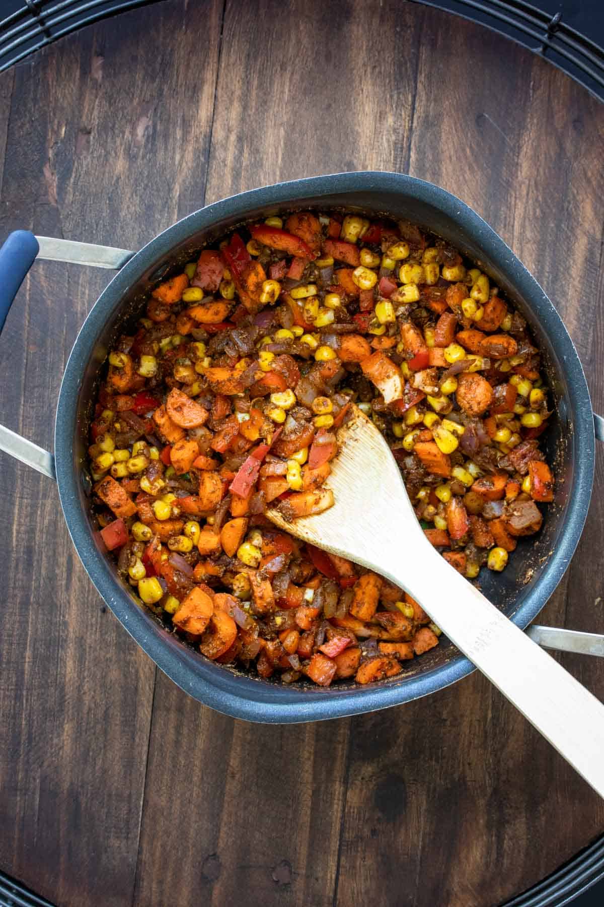 Wooden spoon mixing chopped veggies in a pot