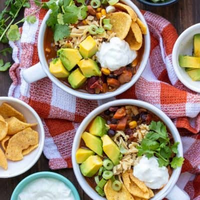 Two soup bowls filled with veggie chili surrounded by ingredients