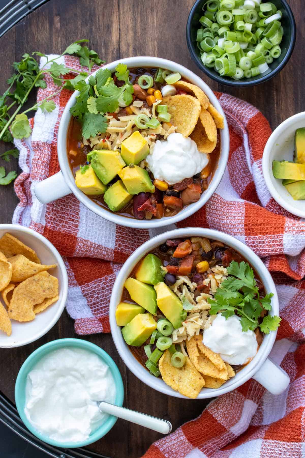 Two soup bowls filled with veggie chili surrounded by ingredients