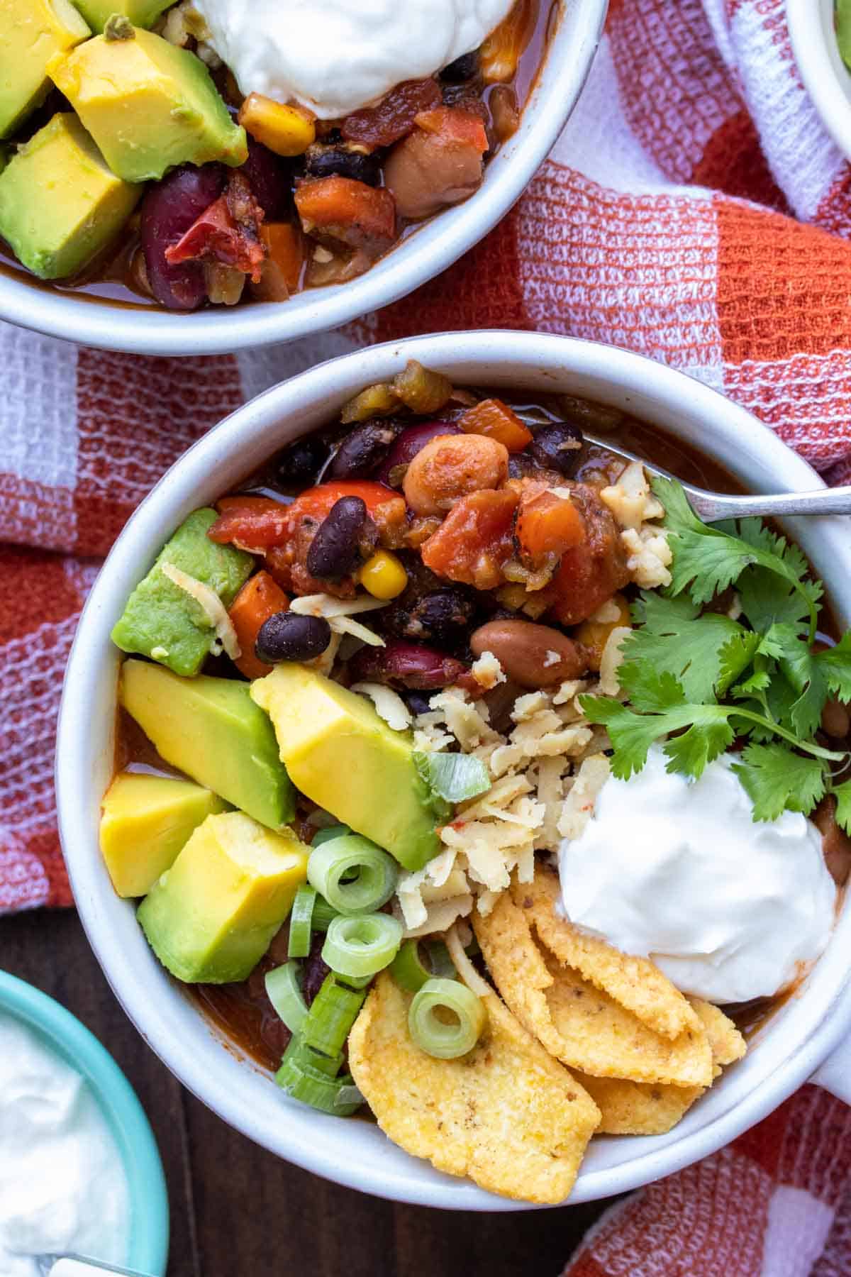 Close up of a bowl of veggie chili and a spoon getting a bite