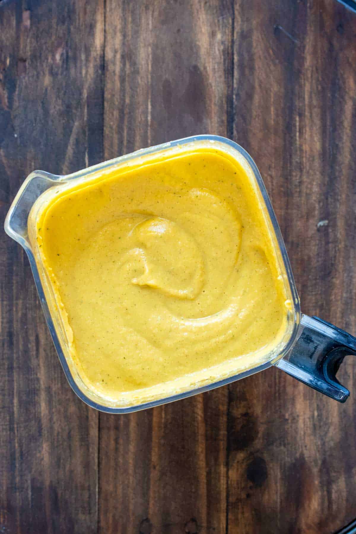 Top view of a blender with thick pureed orange soup in it