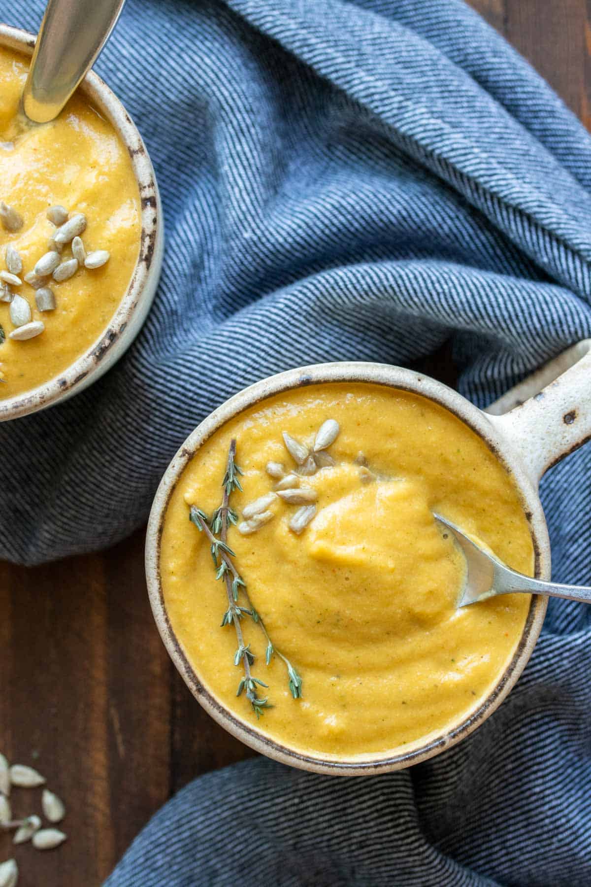 Spoon taking a bite from a mug of creamy pureed winter squash soup