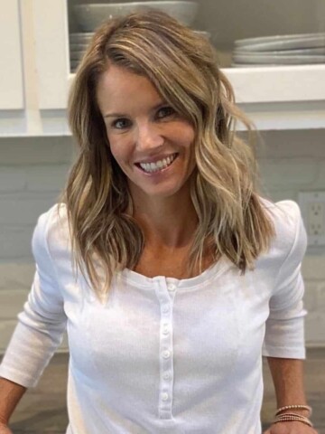 Blond woman in a white shirt leaning against a counter