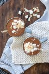 Top view of two grey mugs filled with hot cocoa and topped with whipped cream and marshmallows