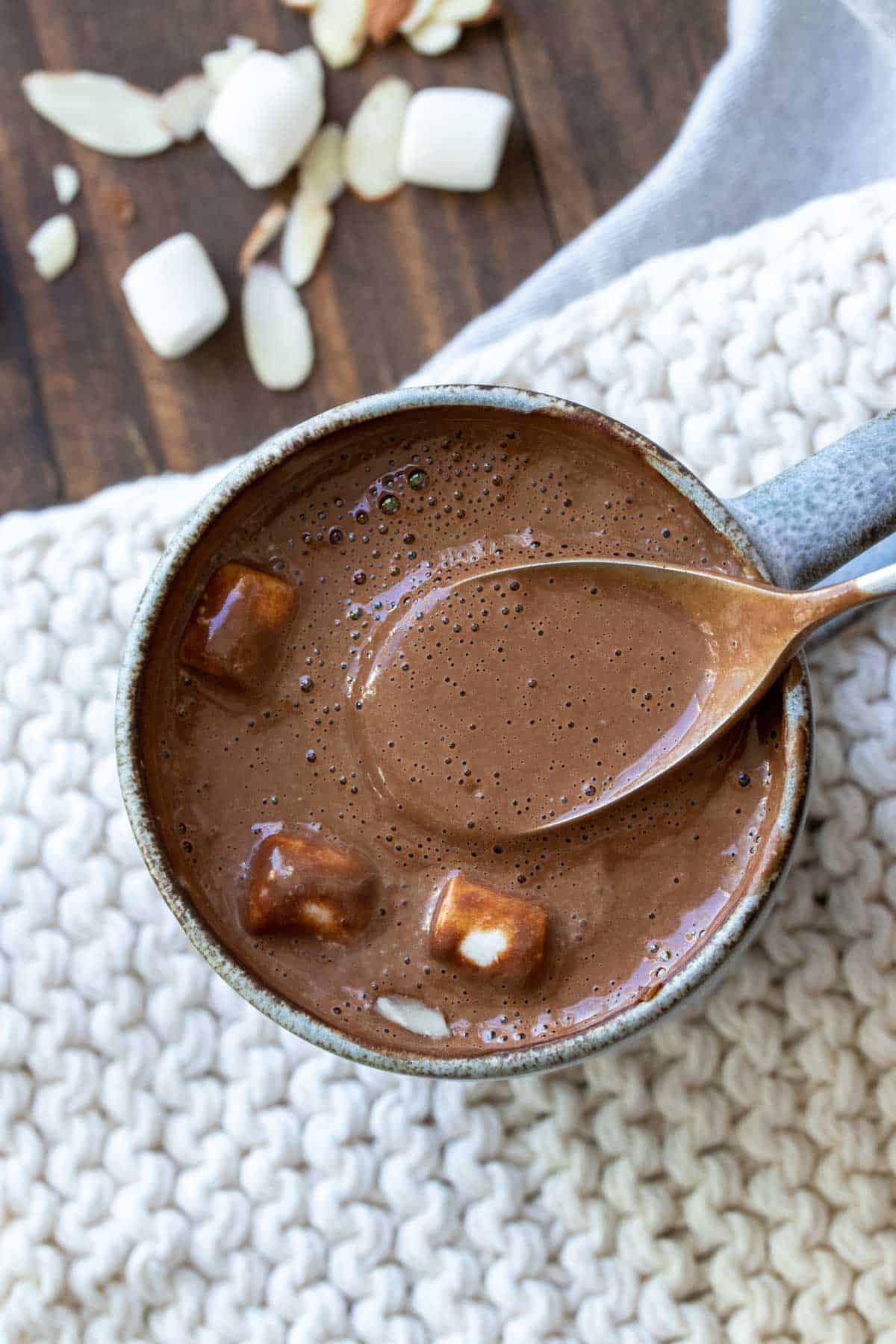 Spoon getting a scoop of thick hot chocolate from a grey mug