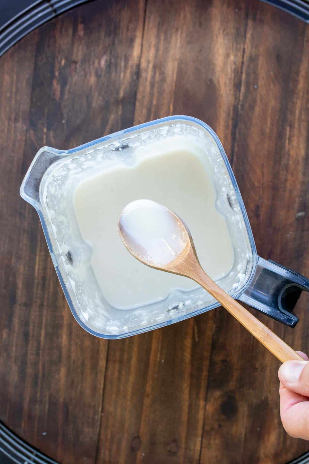 Wooden spoon taken coconut butter out of a blender