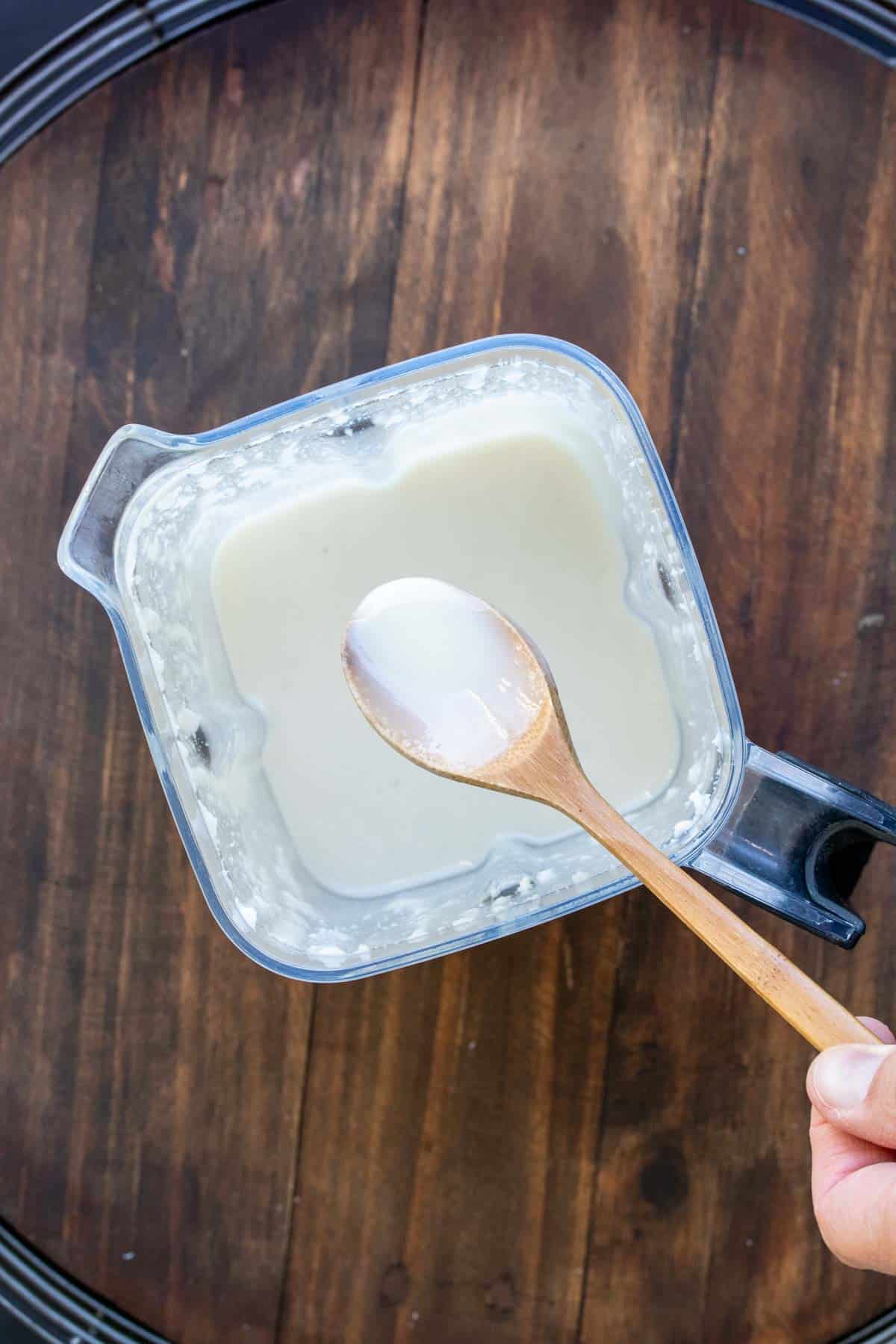 Wooden spoon taken coconut butter out of a blender.