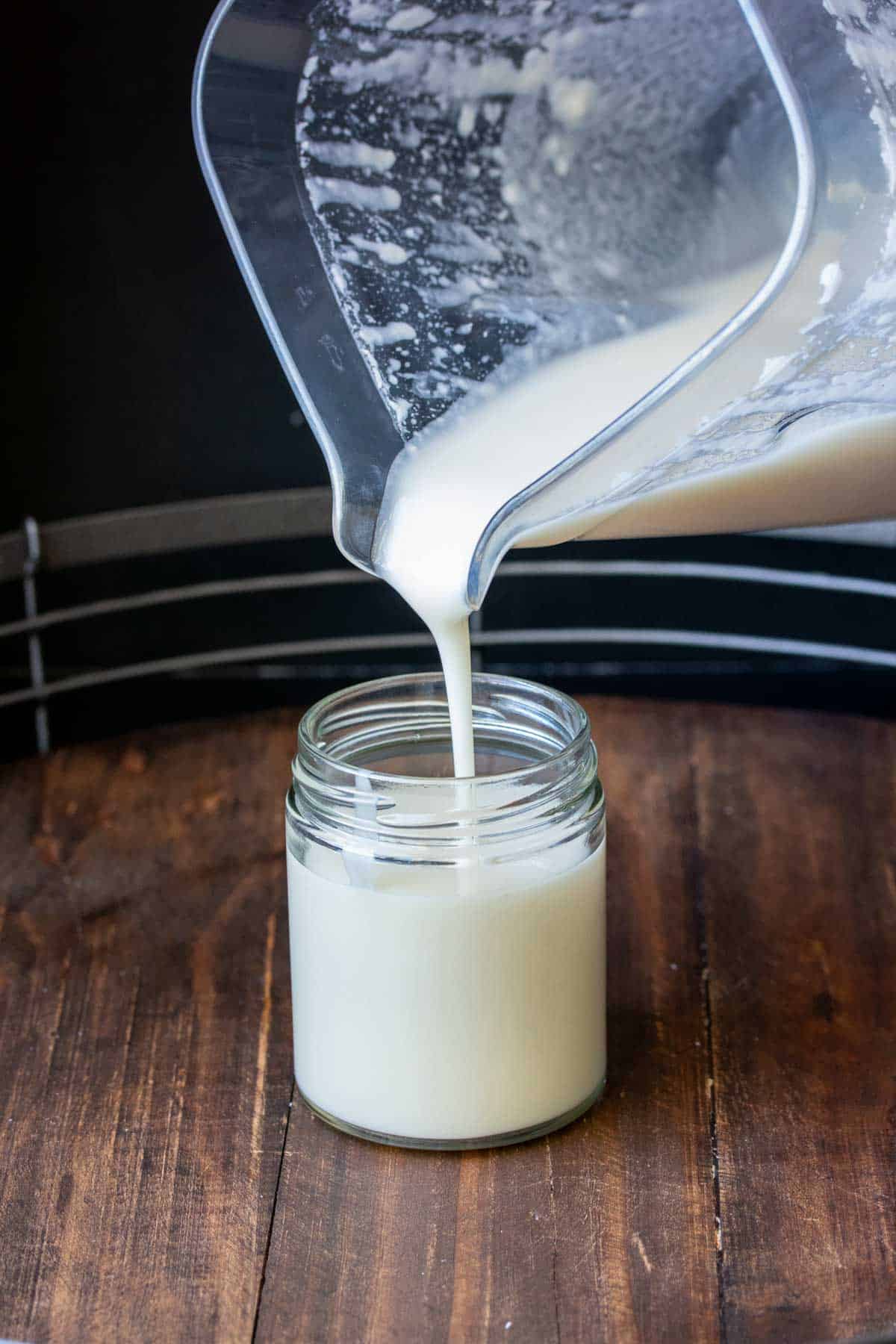 Blender pouring coconut butter into a glass jar.