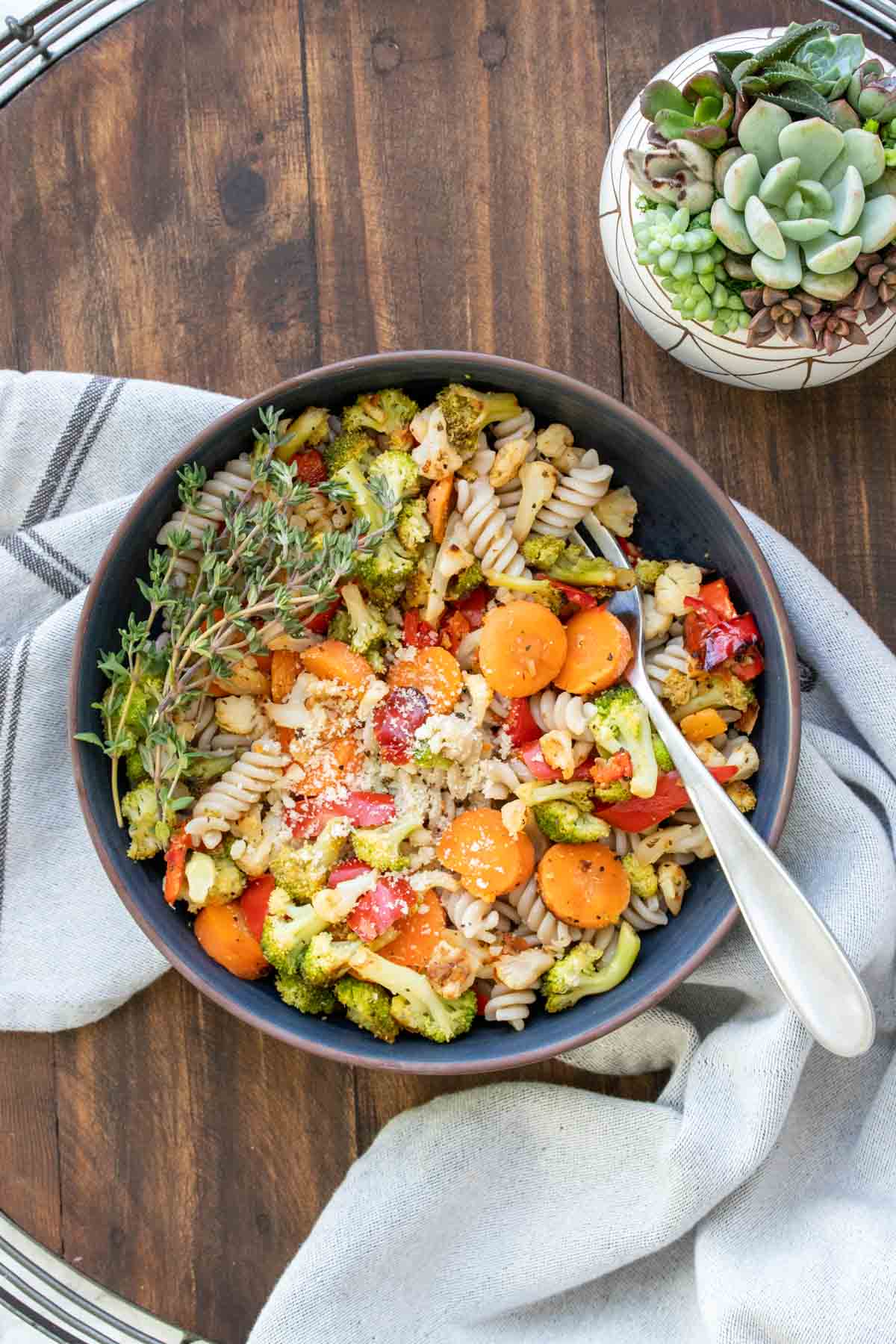 Dark bowl with pasta mixed with veggies and parmesan