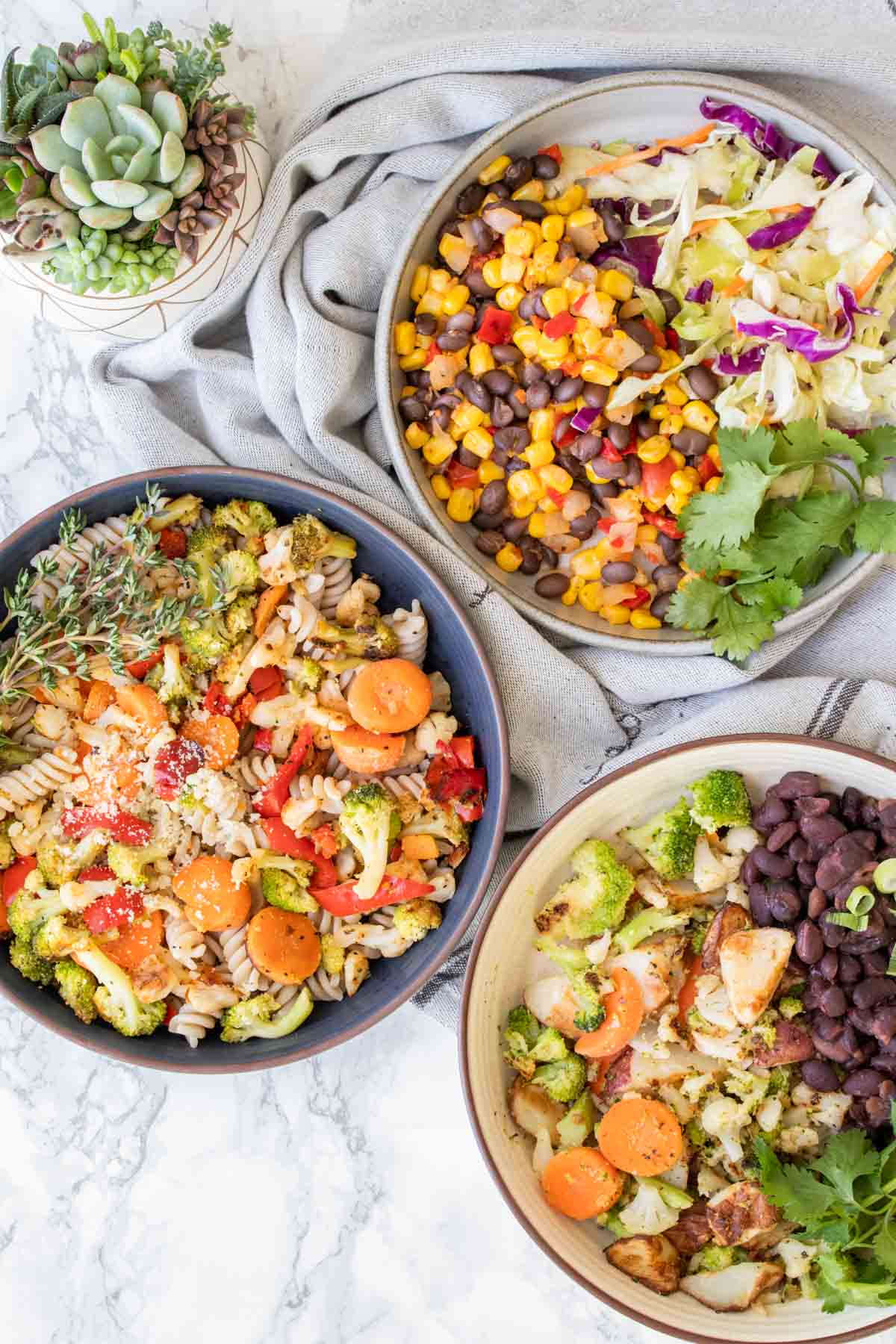 Three bowls filled with veggies mixed with different things on a kitchen towel