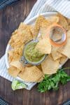 Plate with tortilla chips and a jar of salsa verde with a chip in it