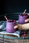 Hands grabbing jars with thick purple smoothies in them