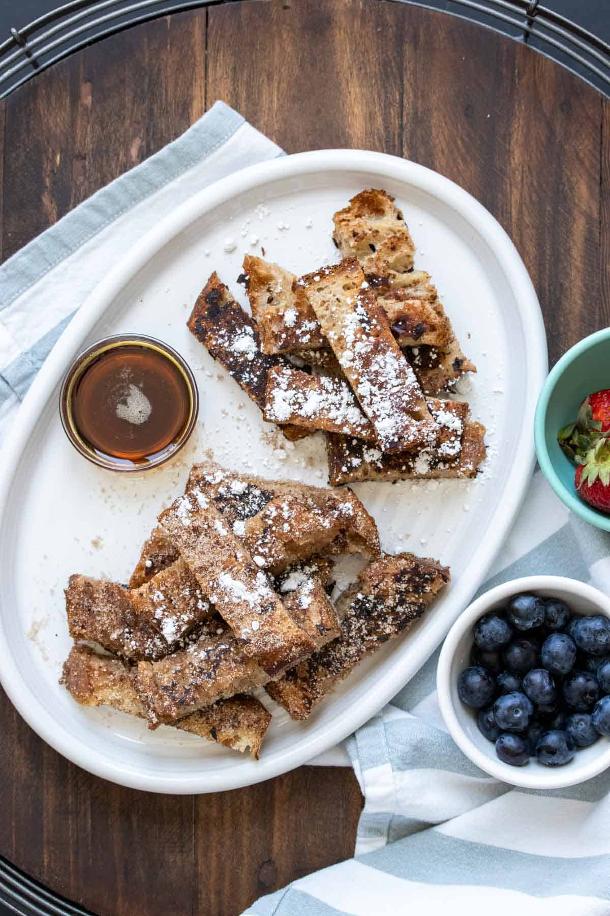 White platter with french toast sticks and bowls of toppings