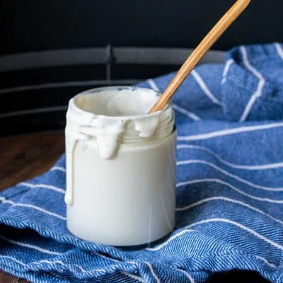 Glass jar filled with a creamy sauce and a wooden spoon