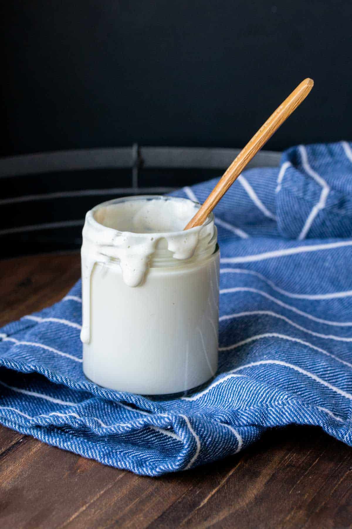 Glass jar filled with a creamy sauce and a wooden spoon