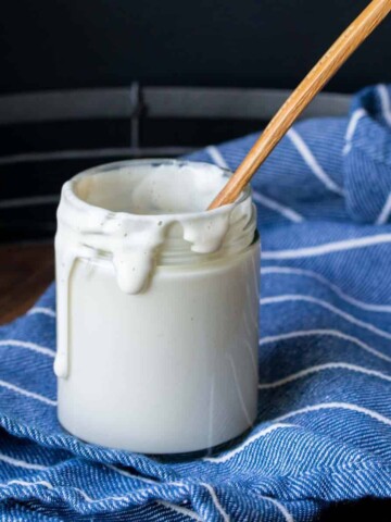 Wooden spoon in a glass jar filled with creamy aioli