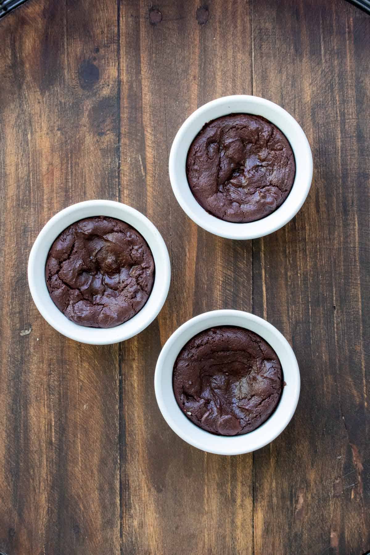 Baked mini chocolate cakes in white ramekins.