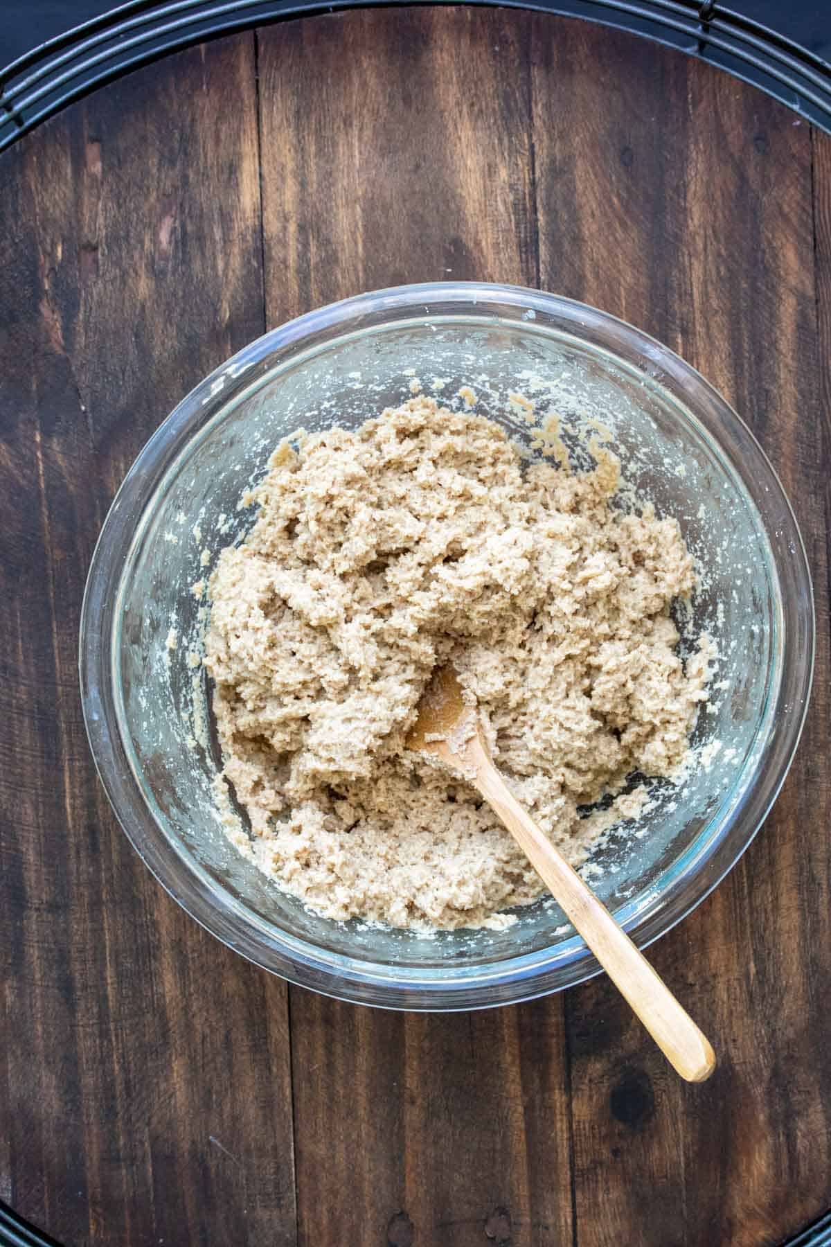 Wooden spoon mixing batter in a glass bowl