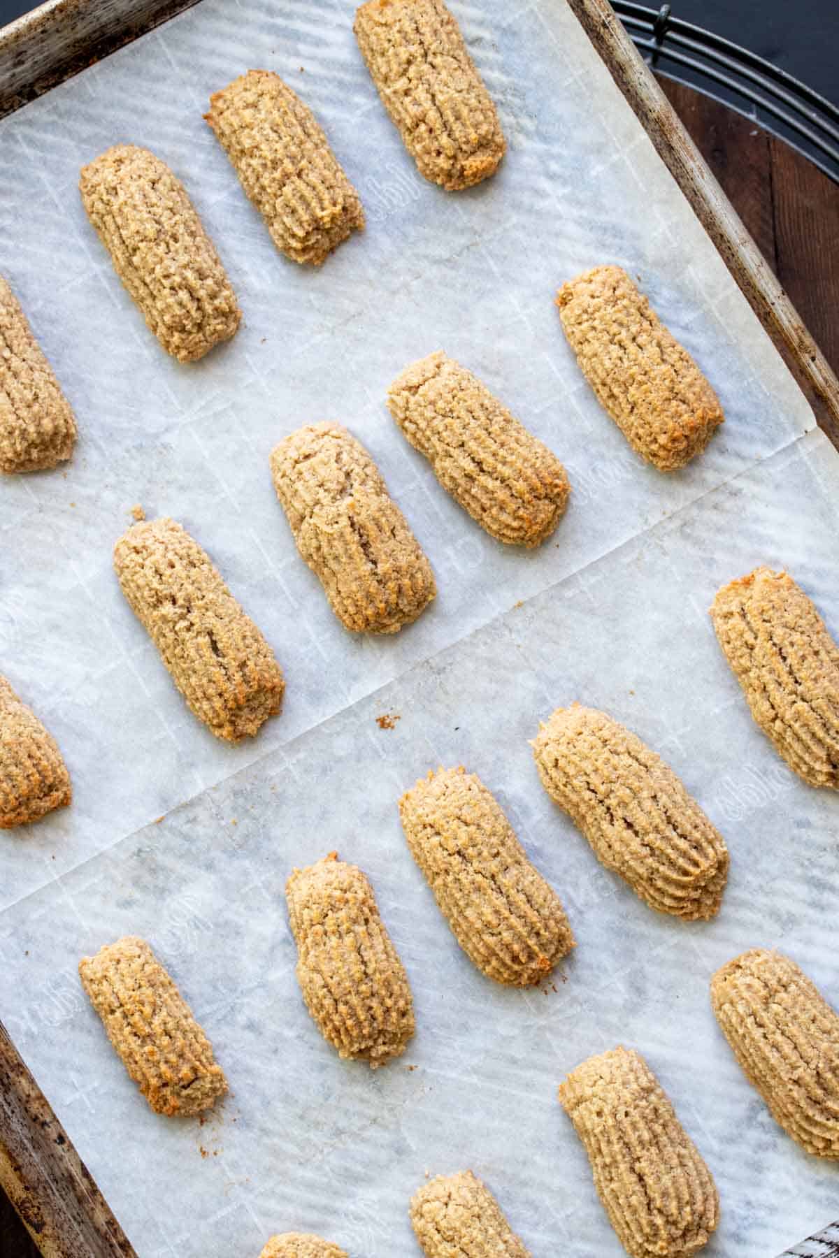 Baked pieces of churros on a parchment lined baking sheet