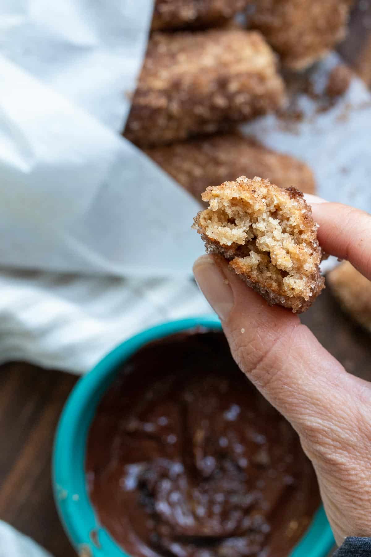 Bitten churro piece being held up by a hand so you can see the center