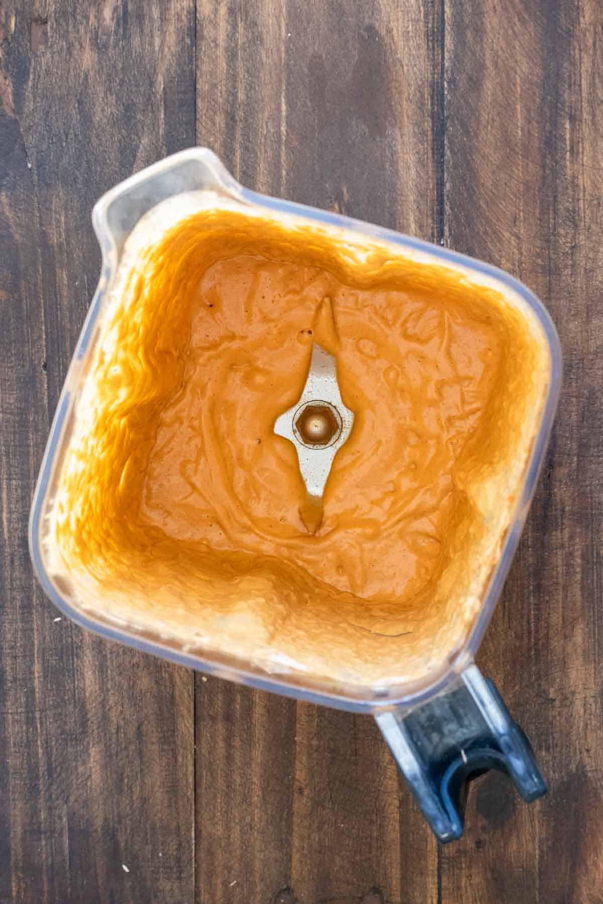 Top view of a blender with an orange colored creamy sauce in it