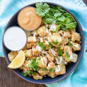 Bowl filled with crispy potato pieces and two small bowls of sauce