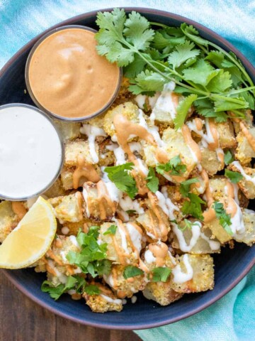 Bowl filled with crispy potato pieces and two small bowls of sauce