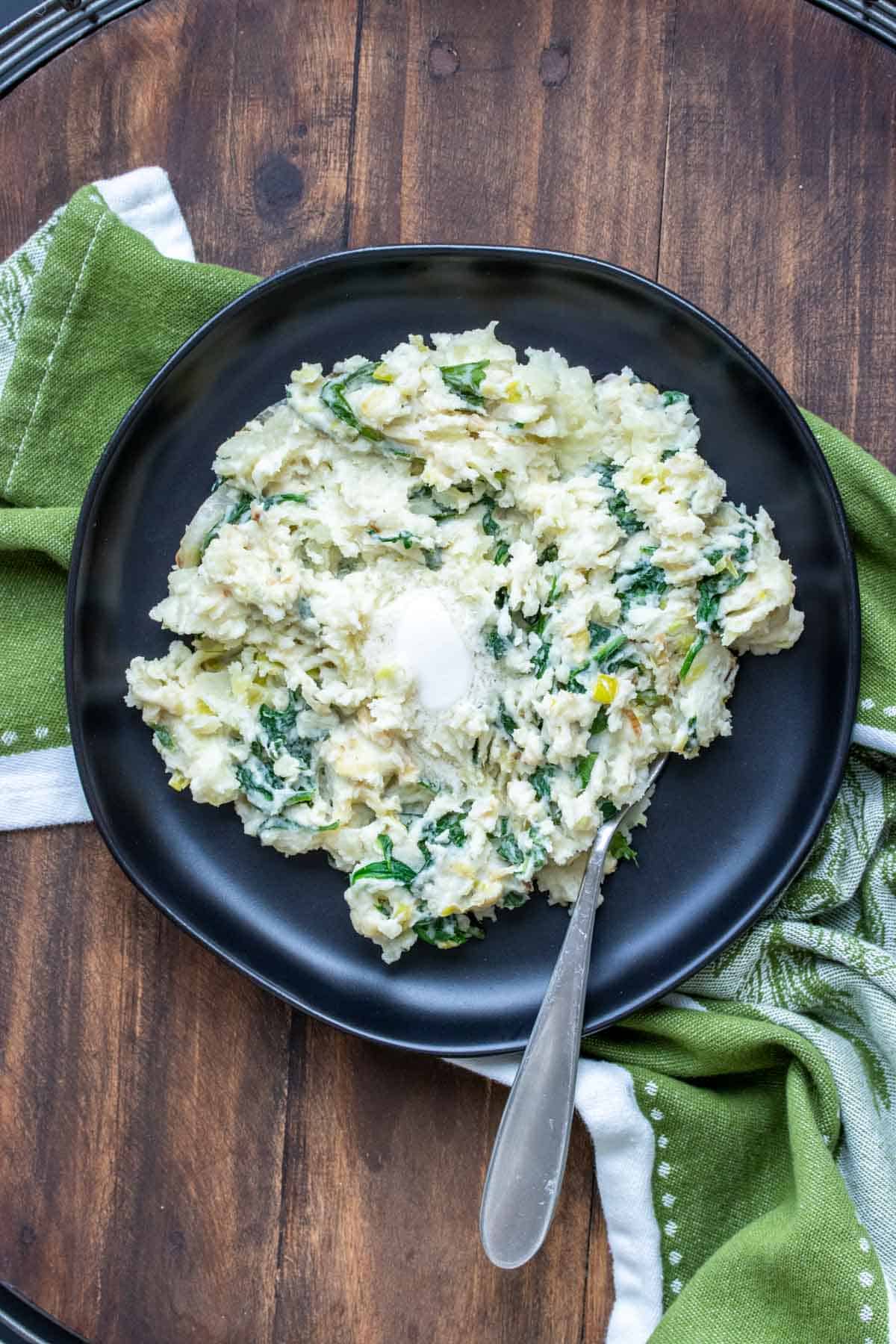 Black plate with colcannon topped with a slice of butter