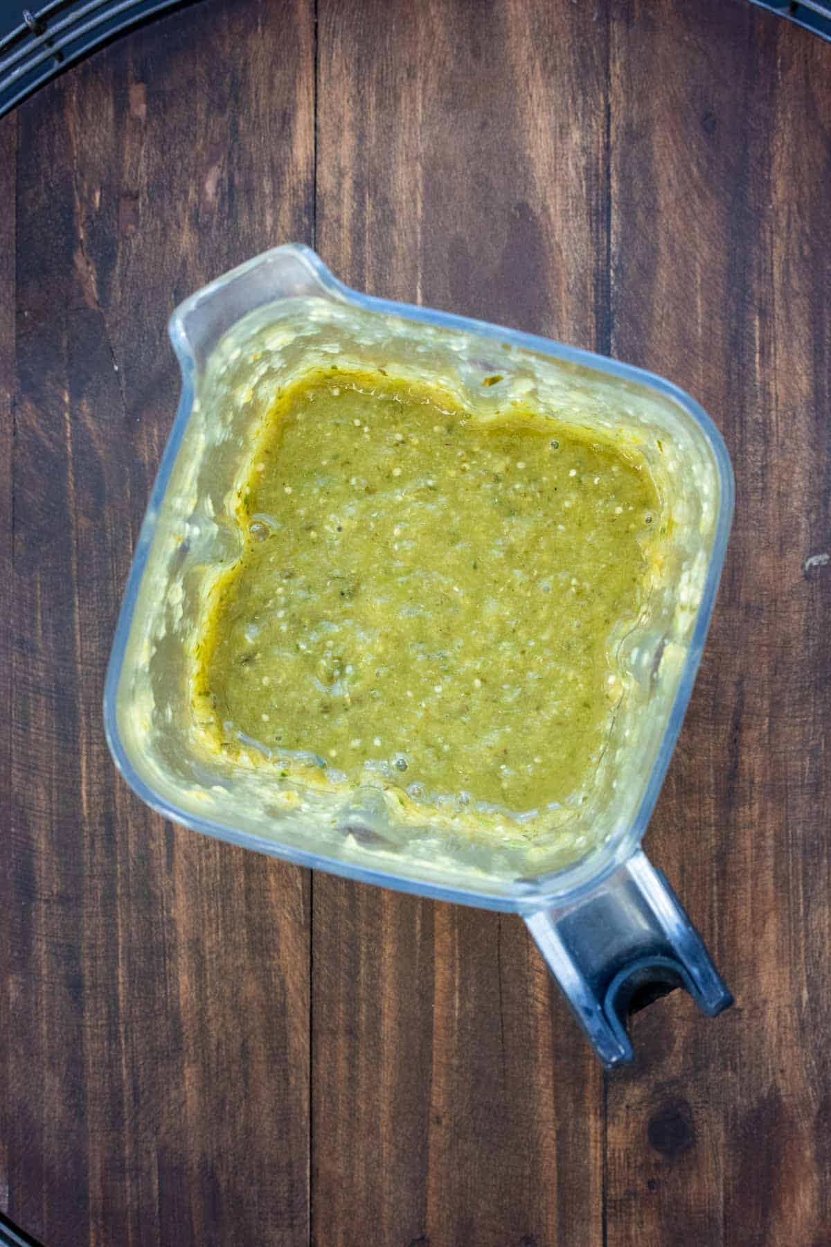 Top view of a blender with green sauce in it.