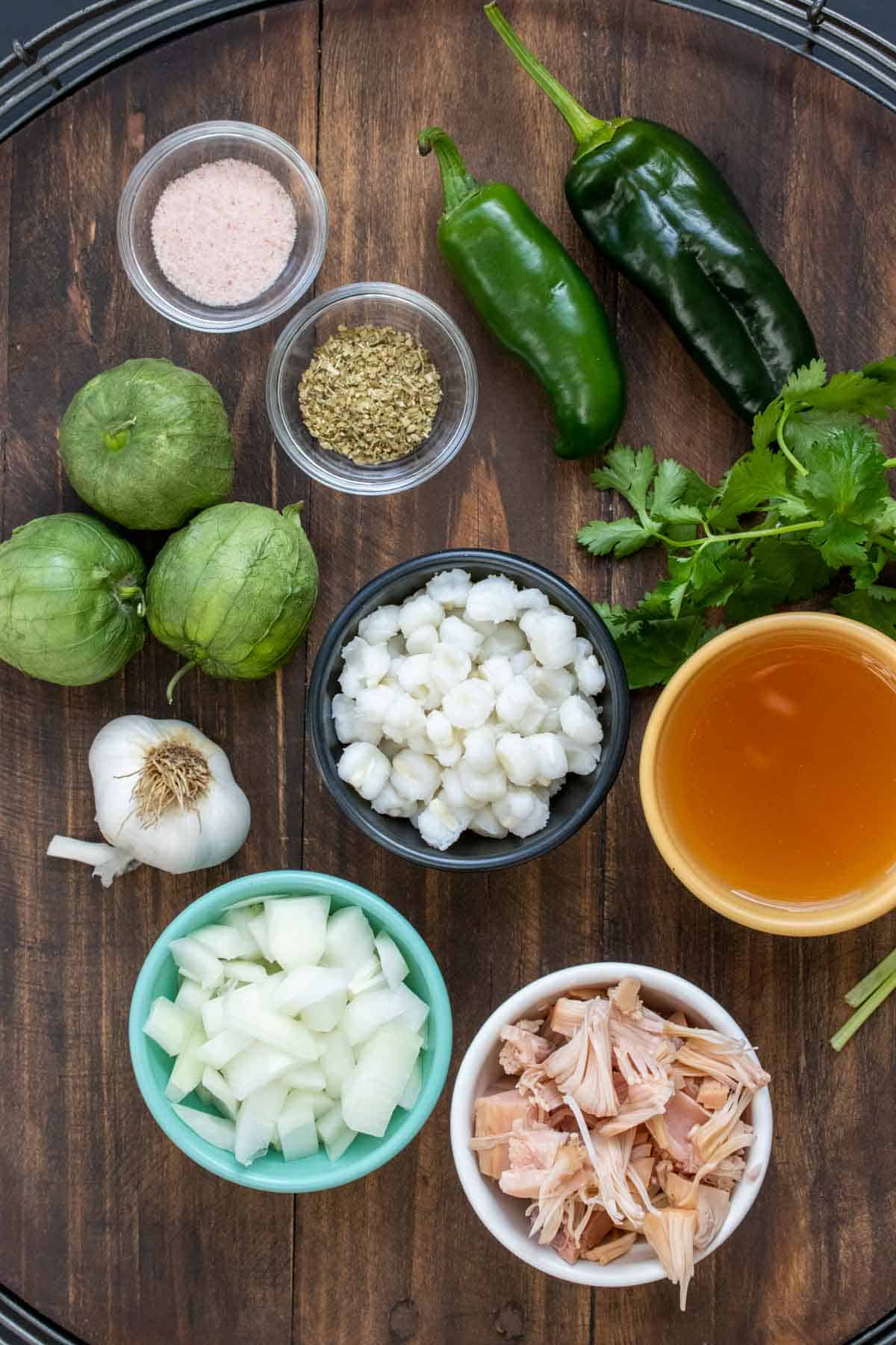 Ingredients needed to make a Mexican pozole verde on a wooden surface.