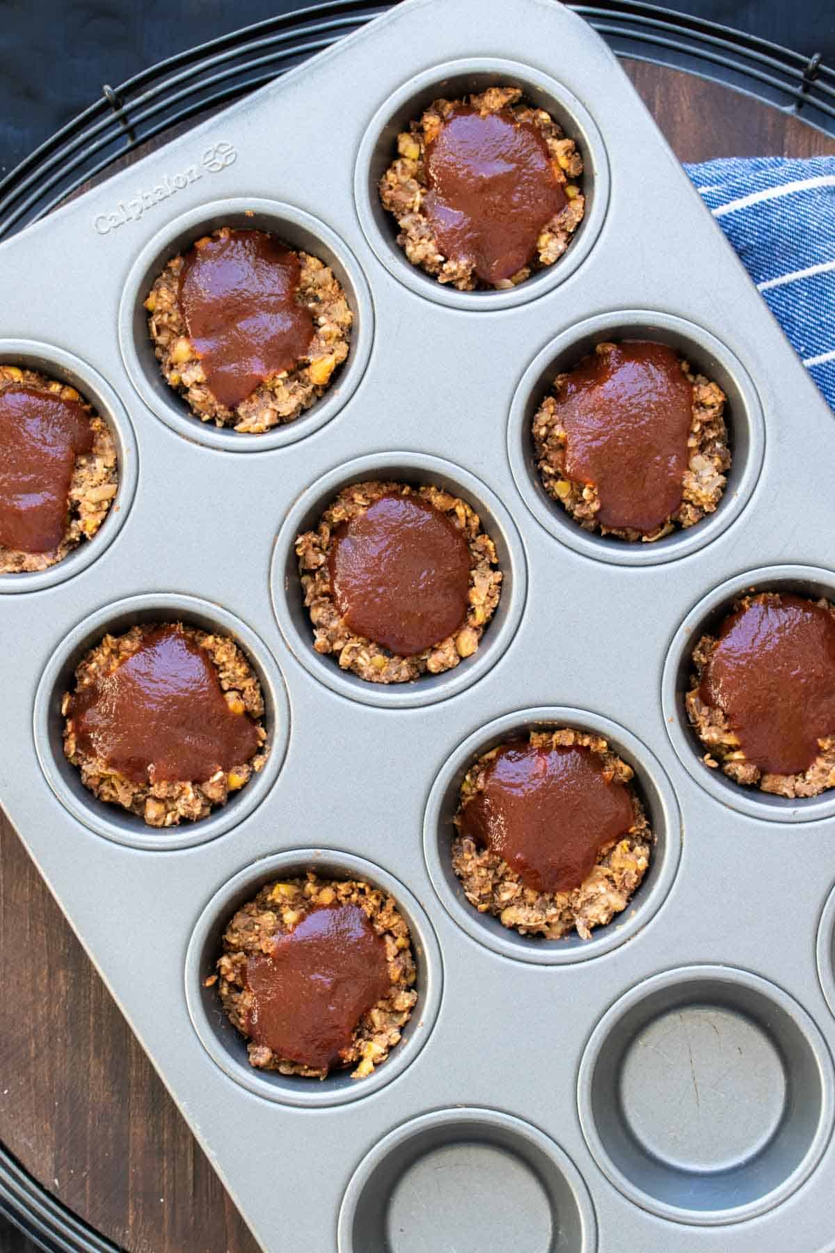 Muffin pan with mini lentil meatloaf cups topped with barbecue sauce