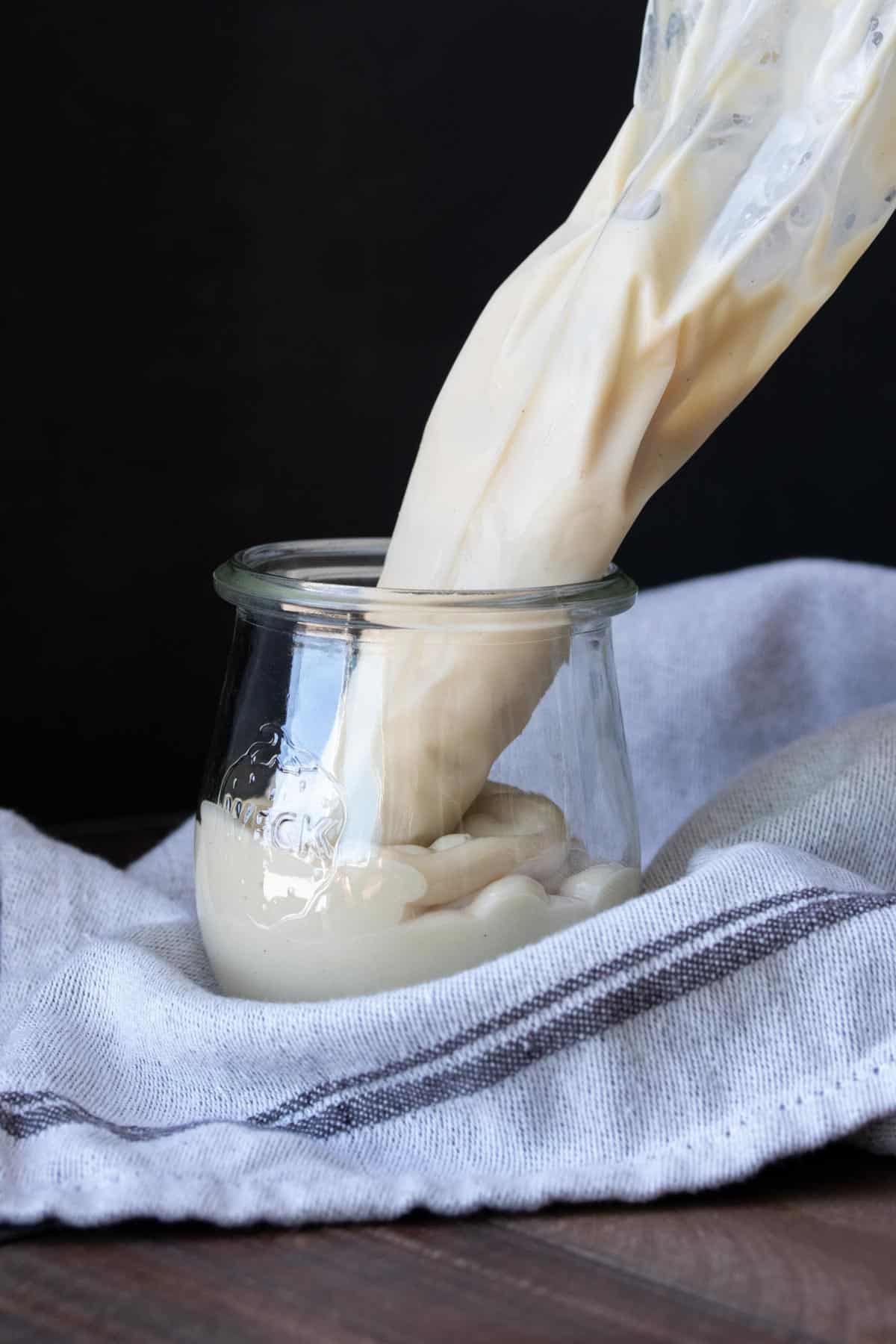 Piping bag filled with cream cheese frosting resting in a glass jar