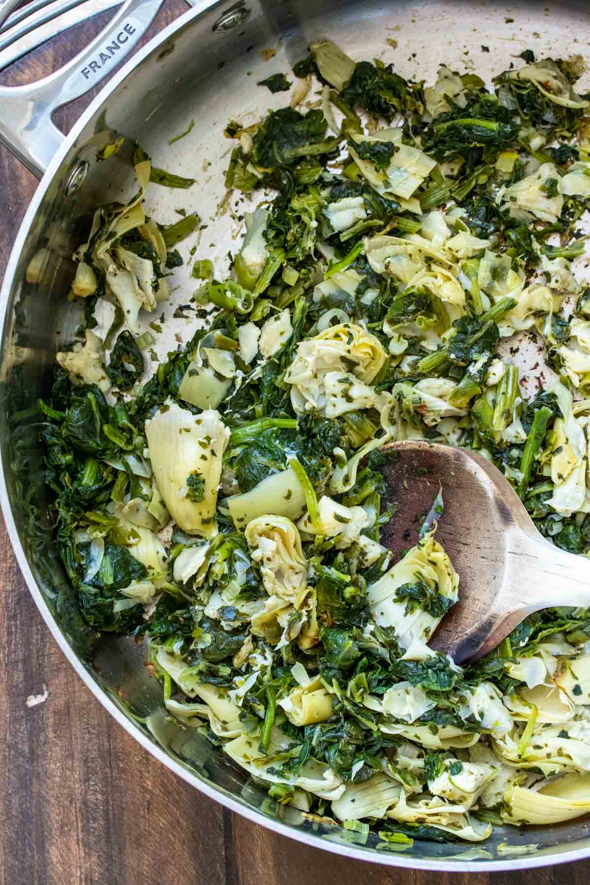 Spinach, artichokes and green onion sautéing in pan